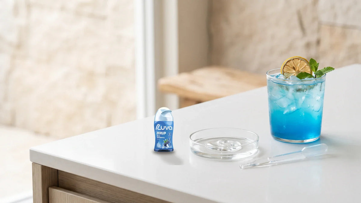 ZERUP by LUVA Blue Raspberry bottle beside a glass dish, a pipette and a glass of blue iced drink