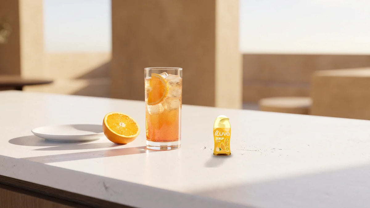 ZERUP by LUVA Orange bottle next to a glass of sparkling orange drink and half an orange